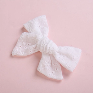 Close-up of white lace bow hair clip featuring intricate daisy embroidery details