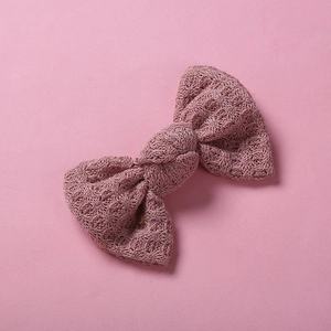 Détail d'un nœud papillon en maille rose montrant la texture du fil et le tissage