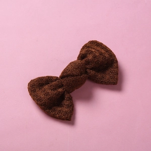 Détail d'une pince à cheveux avec nœud en tricot marron foncé et texture crochetée