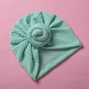 Details zur Waffelstruktur und dem Donut-Knoten der babygrünen Turban-Mütze
