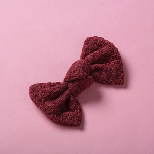 Détail d'une barrette à nœud en tricot bordeaux avec texture gaufrée pour enfants