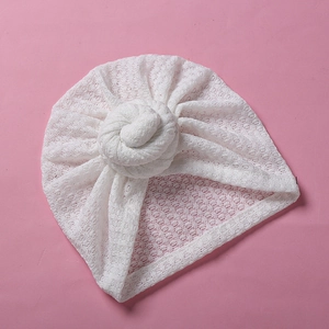 Detail der weißen hohlen Strickstruktur und des Donut-Knotens der Baby-Turbanmütze