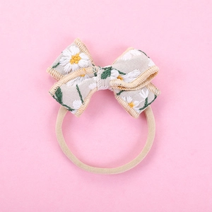 Close-up of embroidered daisy pattern on linen bow headband with soft nylon strap