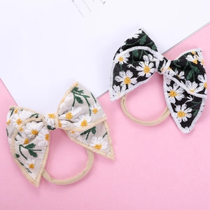 Close-up of baby nylon headbands with embroidered daisy patterns in black and beige tones