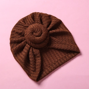 Detail einer braunen Baby-Turbanmütze aus Waffelstrick mit dekorativem Spiralknoten