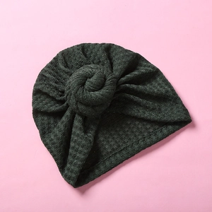 Detaillierte Waffelstrick-Textur und Spiralknoten an der dunkelgrünen Babymütze