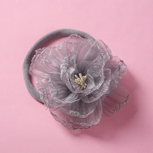 Macro detail of a grey chiffon flower headband with white stamens and soft elastic band