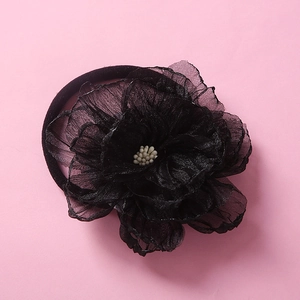 Detail of multi-layered black mesh flower headband with cream center on pink backdrop