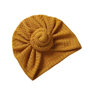 Ingwergelbe Waffelstrick-Babyturban-Mütze mit Vintage-Knoten auf weißem Hintergrund