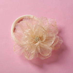 Detail of soft champagne pink organza flower on white elastic nylon baby headband