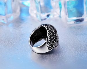 Macro shot of gothic skull ring with floral engraving on blue ice surface