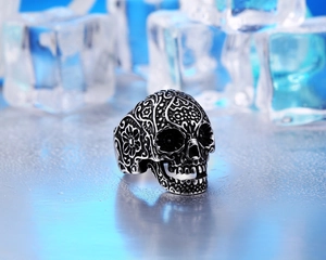 Close-up of vintage skull ring with intricate floral carvings on ice background