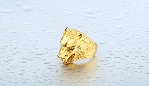 Close-up of golden wolf head ring detail showing intricate carving on polished steel