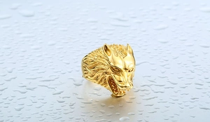Macro shot of gold wolf head ring with detailed fur texture on water drop background