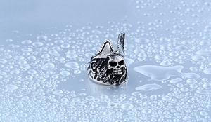Détail macro d'une bague de pirate rétro en acier inoxydable sur fond de gouttes d'eau