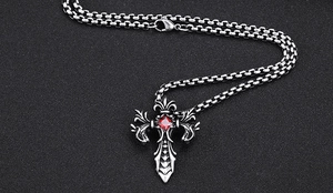 Makro-Detail des gotischen Drachenkreuz-Anhängers mit rotem Edelstein und Stahl-Textur