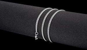 Macro view of silver curb chain necklace with lobster clasp on black display stand