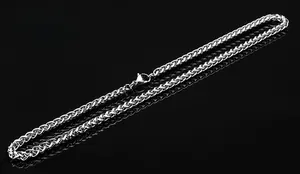 Vista macro di una catena a spiga in argento con chiusura a moschettone su nero