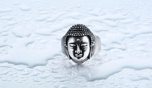 Detail of vintage stainless steel Buddha head ring on a calm water reflection background