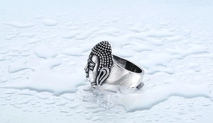 Macro shot of Buddha head carving on vintage stainless steel ring with water drops