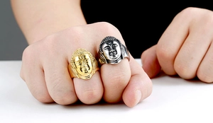 Detail of Buddha head rings in gold and silver finish worn on fingers, metal texture