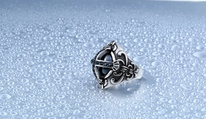 Détail de bague vintage en acier avec pierre noire et motifs de croix gothique