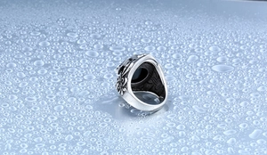 Détail macro de la bague vintage pour homme en acier avec pierre noire et motifs de croix