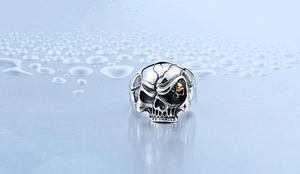 Nahaufnahme eines Punk-Totenkopfrings mit Distressed-Silber-Textur und goldenem Auge