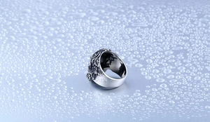 Detail of vintage skull ring with rose relief on water-splashed metal surface