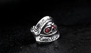 Macro shot of gothic skull ring with red gemstone eyes and Give/Take engraving on band
