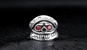 Macro shot of gothic silver skull ring with deep red gemstone eyes and engraved text