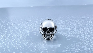Detailed macro view of retro skull ring with vintage finish and steel texture on water droplets
