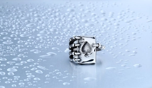 Close-up of vintage Ace of Spades poker ring with skull claw details and water droplets