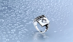Detailed side view of punk gothic skeletal hand holding an Ace of Spades steel ring