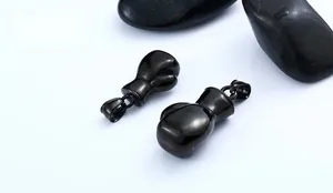 Polished black stainless steel boxing glove pendant displayed on natural dark stones