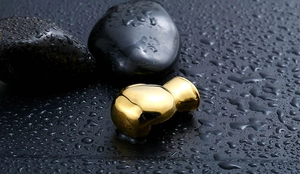 Detailed macro shot of a golden boxing glove pendant on a wet black textured surface