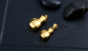Detailed view of two gold boxing glove pendants in different sizes on black stones