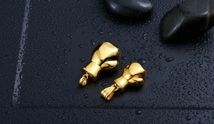 Detailed view of golden boxing glove pendants on dark stone with water drops