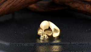 Detailaufnahme eines goldenen Totenkopfrings mit polierter Metalloberfläche und Licht