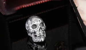 Detailed macro view of vintage skull ring with intricate floral carvings on dark wood