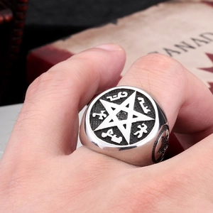 Gros plan d'une bague pentagramme vintage avec runes sur la main sur fond de papier rétro