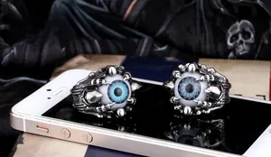 Macro shot of gothic dragon claw ring featuring a detailed blue eyeball on dark fabric