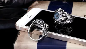 Macro detail of punk skull rings with blue eye inlay and textured antique silver band