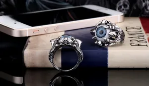 Detailed macro view of dark gothic silver rings featuring blue eyeballs and eagle claws