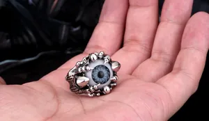 Macro view of dark gothic silver ring with realistic blue eye detail and sharp eagle claws