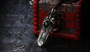 Macro detail of vintage feather pendant with black gemstone on a wooden jewelry box