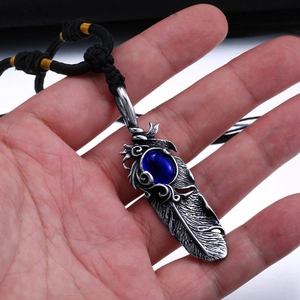 Vintage feather pendant necklace with a blue gemstone and adjustable black braided cord