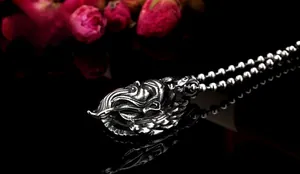 Detail view of retro stainless steel Guan Gong pendant with bead chain on a dark surface