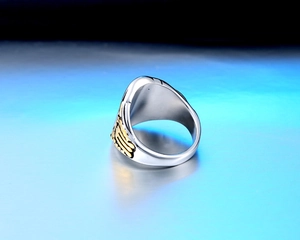 Macro shot of stainless steel biker ring featuring golden eagle wings and a polished finish