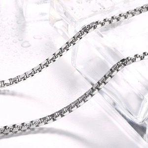 Polished stainless steel box chain necklace reflecting on ice cubes with water droplets